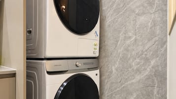 Eine gestapelte Waschmaschine und ein Trockner in einem Badezimmer mit Marmorwand.