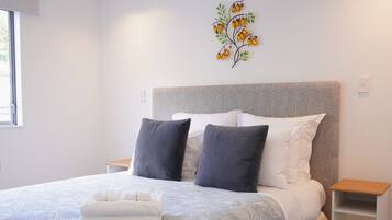 A neatly made bed with a patterned bedspread, two pillows, and a folded towel.