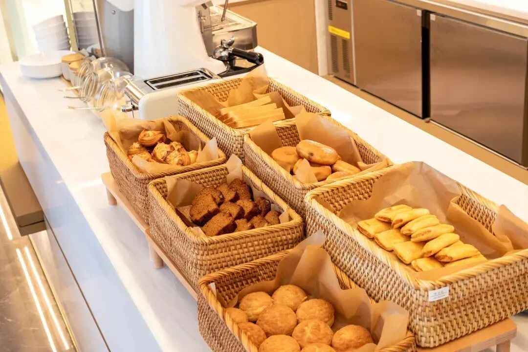 A buffet with wicker baskets containing various baked goods.