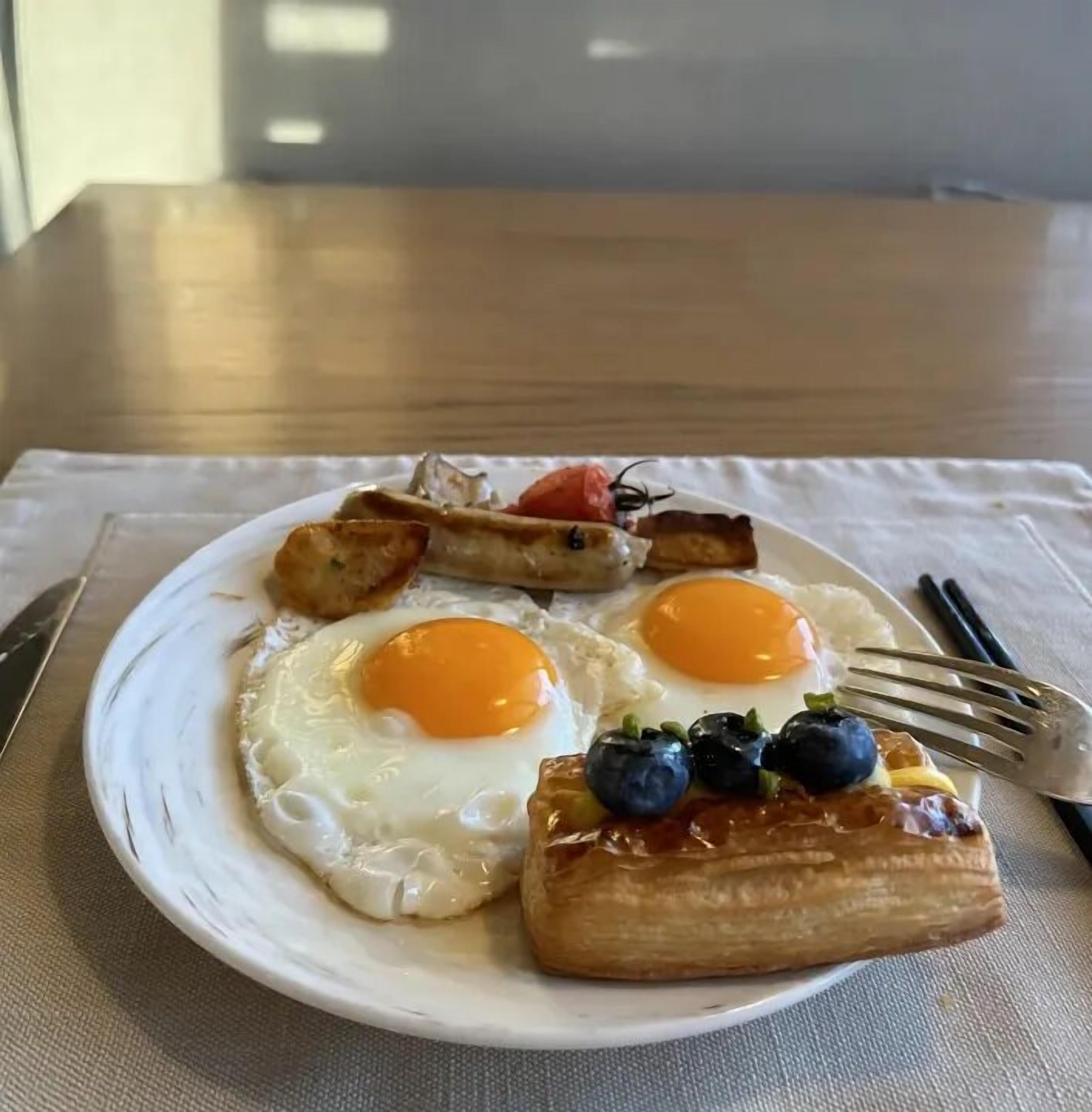 Un plato de desayuno con huevos, tostadas y arándanos sobre un plato blanco.