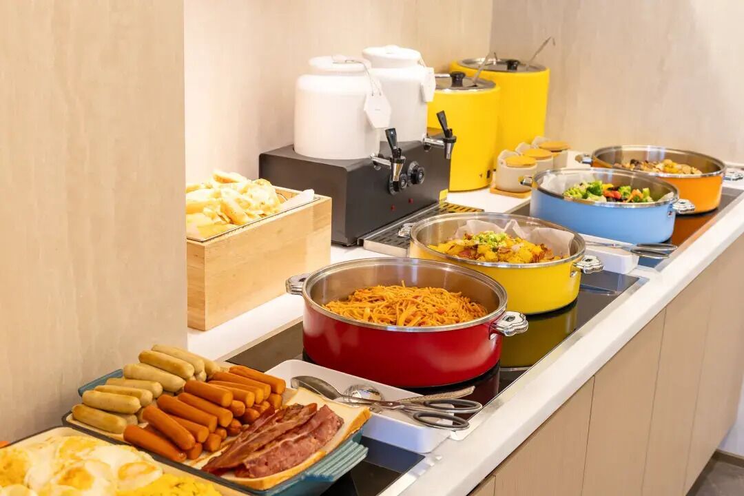 Un bufé con diferentes opciones de comida, como hot dogs, queso y ensaladas.