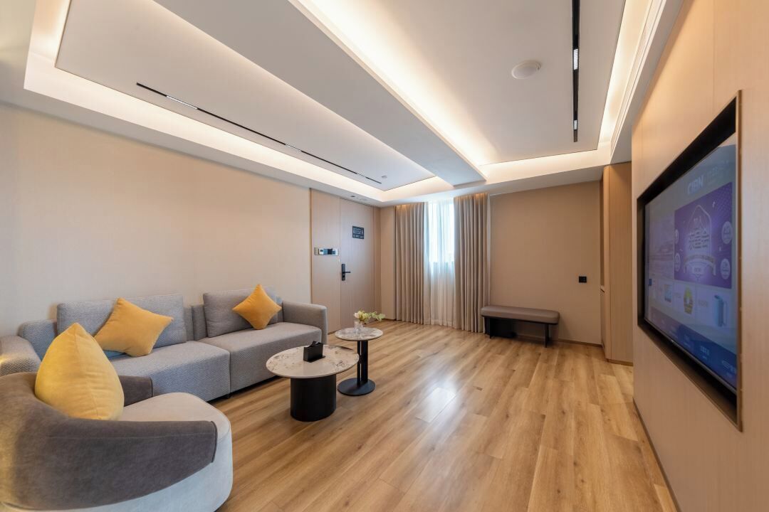 A modern living room with a sofa, armchair, coffee table, and a TV screen.