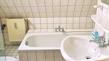 Een badkamer met een bad, wastafel, toilet en een radiator.