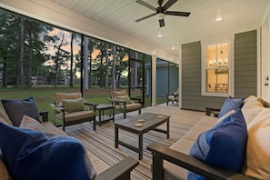 A covered outdoor seating area with a ceiling fan, a dining table, and a view of a wooded area. - New Construction 4BR Golf Retreat - Golf Course Views - 3 Miles to Sunset Beach (Sunset Beach)