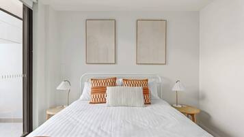 Une chambre moderne avec un grand lit, deux tables de chevet et deux œuvres d’art accrochées au mur.