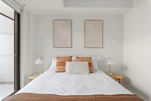 A modern bedroom with a large bed, two bedside tables, and two wall-mounted artworks.