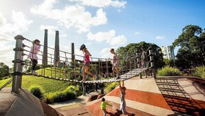 Ein Spielplatz im Freien mit einer Seilbrücke und Klettergerüsten.