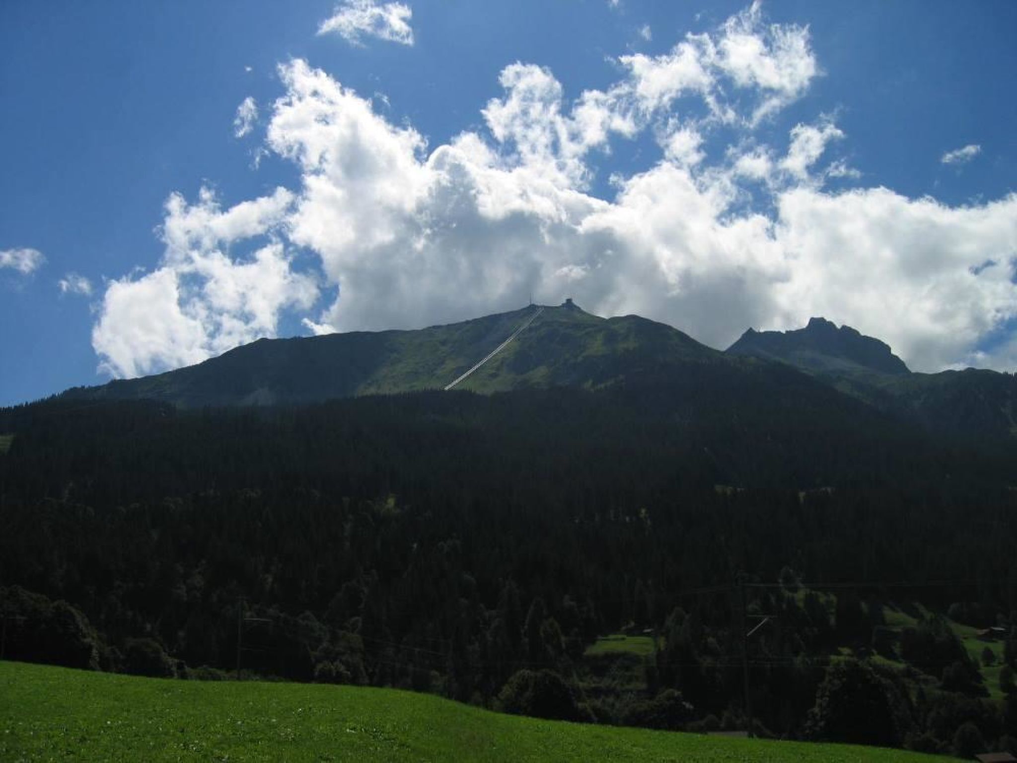 Un paisaje montañoso con cielo despejado y un primer plano cubierto de hierba.
