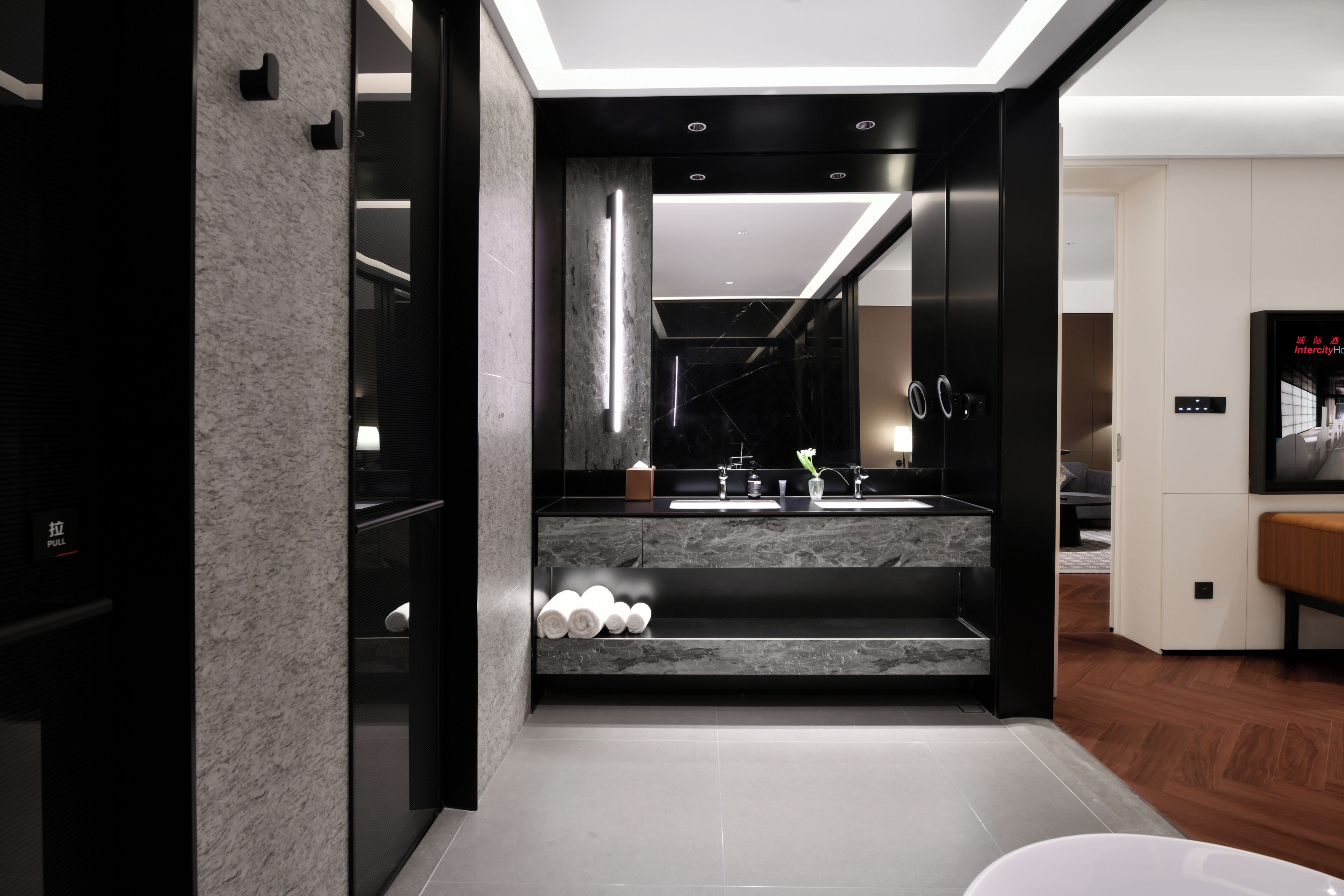 Uma casa de banho moderna com lavatório de mármore, um espelho grande e um toucador preto.