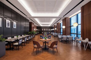Une salle de conférence spacieuse, dotée de nombreuses tables et chaises, de grandes fenêtres et d’un design de plafond moderne.