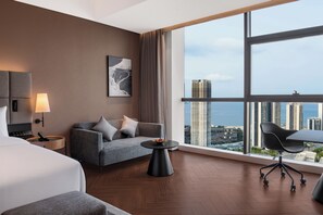 Ett modernt hotellrum med ett stort fönster, en soffa, ett litet bord och en säng.
