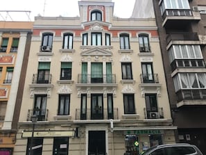 Um edifício de vários andares com uma farmácia no andar térreo, varandas e um estilo arquitetônico clássico.