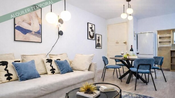A modern living room with a sofa, coffee table, and dining area. - Atocha VI (Madrid)