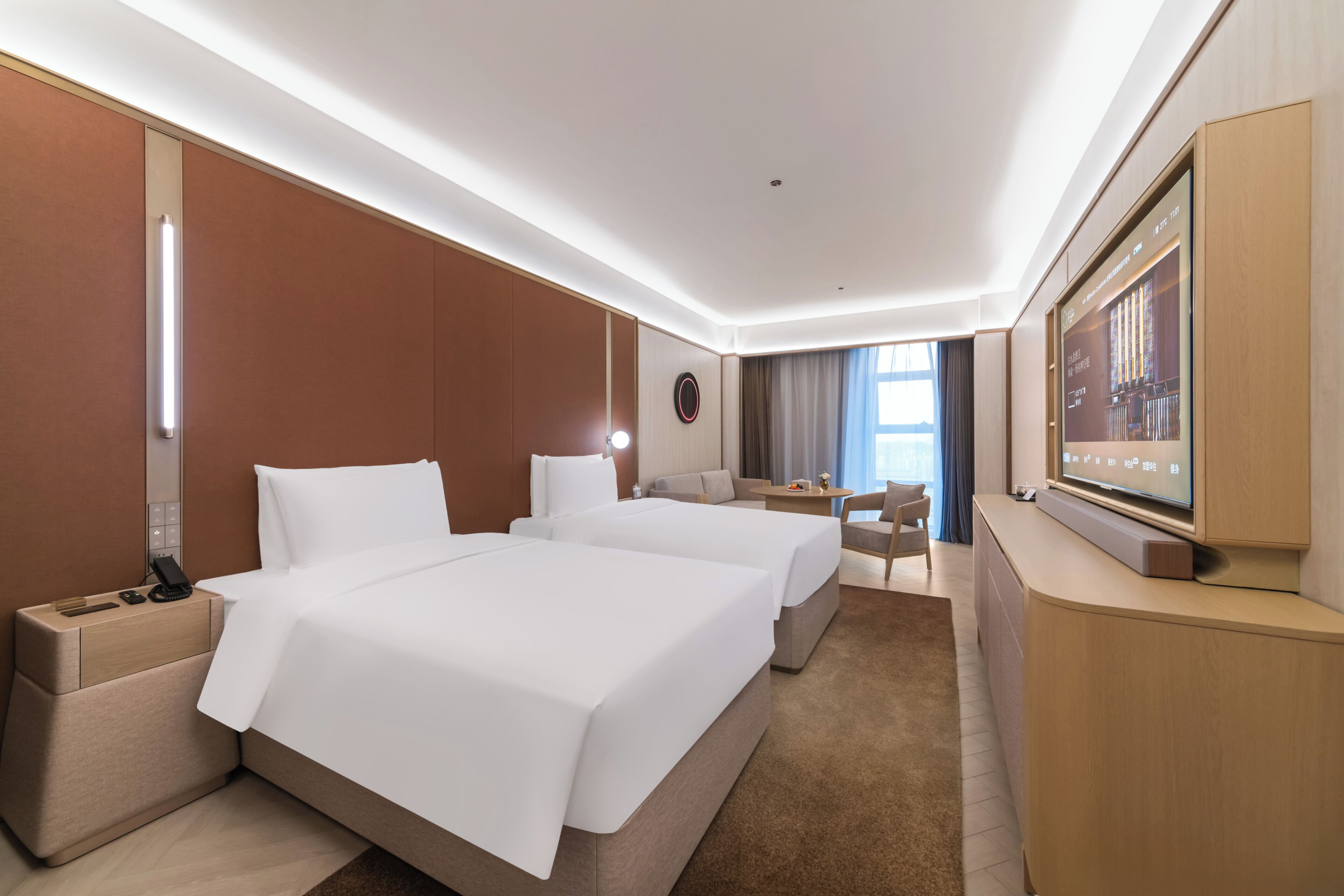 Une chambre d’hôtel avec deux lits, un bureau, une chaise, une télévision et une grande fenêtre.