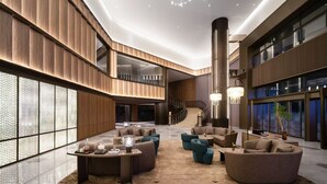 A spacious lobby with a central seating area, a staircase, and a large window.