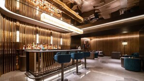 A bar area with a high counter, stools, and a seating area with sofas and a round table.