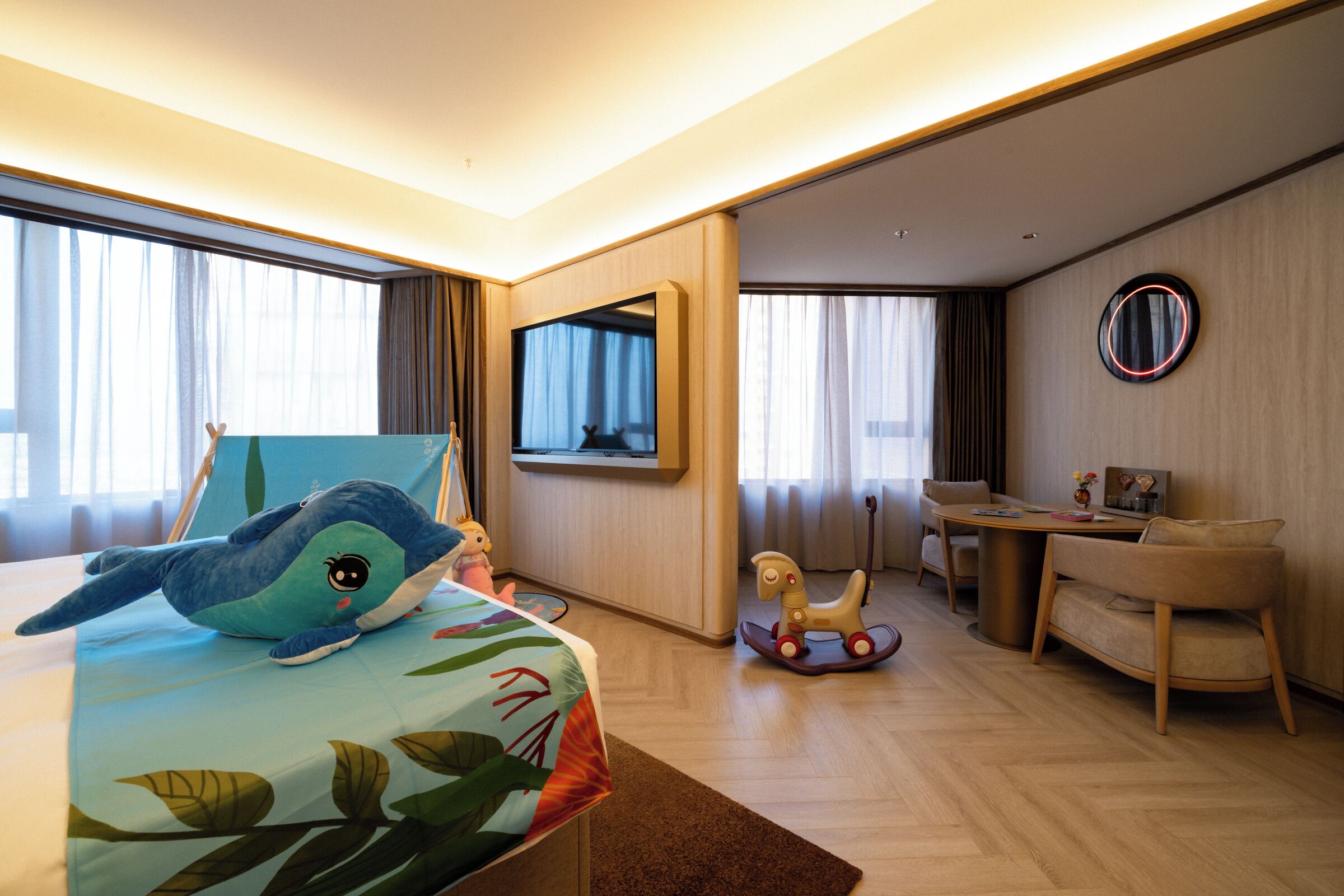 Habitación de hotel con cama, escritorio, silla, pequeña mesa, televisión y ventana con cortinas.