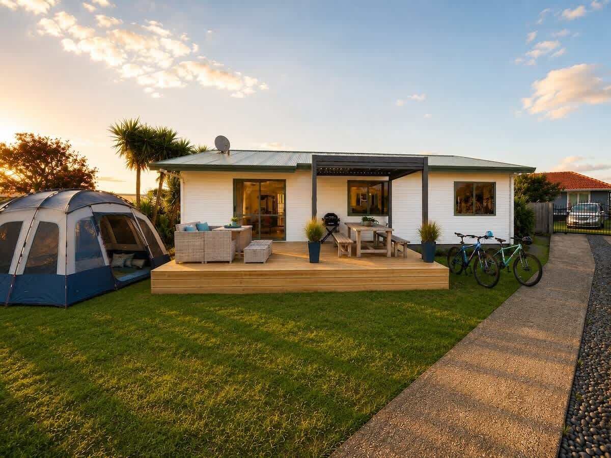 Une maison de plain-pied avec un patio couvert, une tente et des vélos.