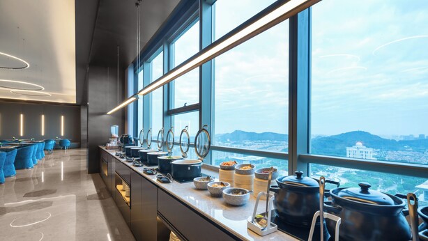 Uma cozinha moderna com serviço de buffet, grandes janelas e vista para a cidade.