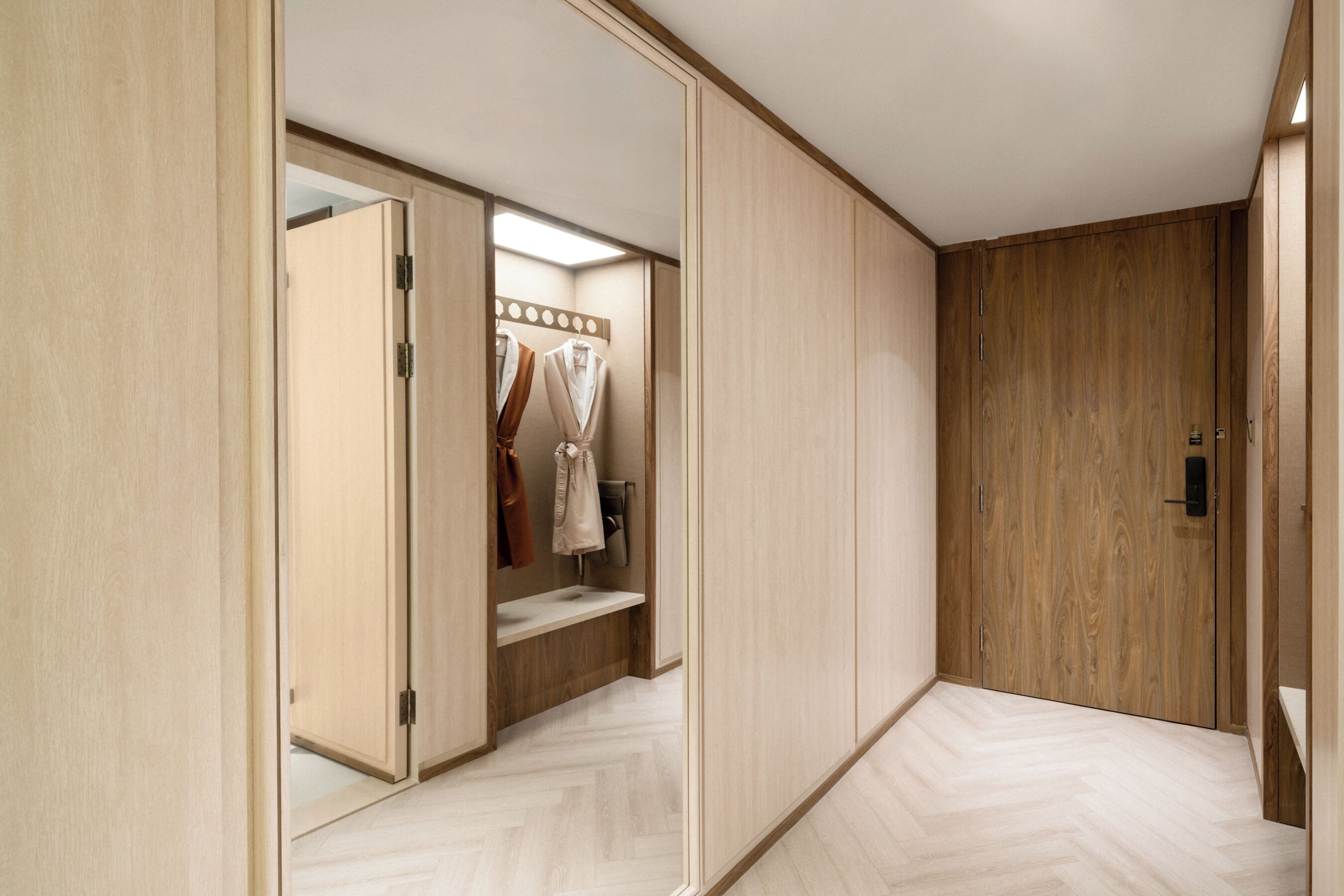 A room with a wooden wardrobe, a mirror, and a bench.