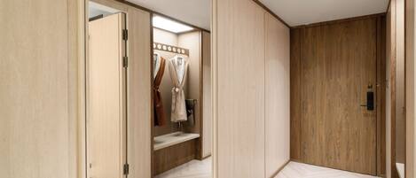 A room with a wooden wardrobe, a mirror, and a bench.