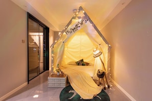 A tent-like room with a bed, a teddy bear, and a sign with Japanese characters.
