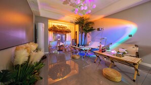A modern interior with a ceiling light fixture, a large plant, a wooden table, and a seating area. - Local Vibe Downtown Guesthouse (Zhangjiajie)