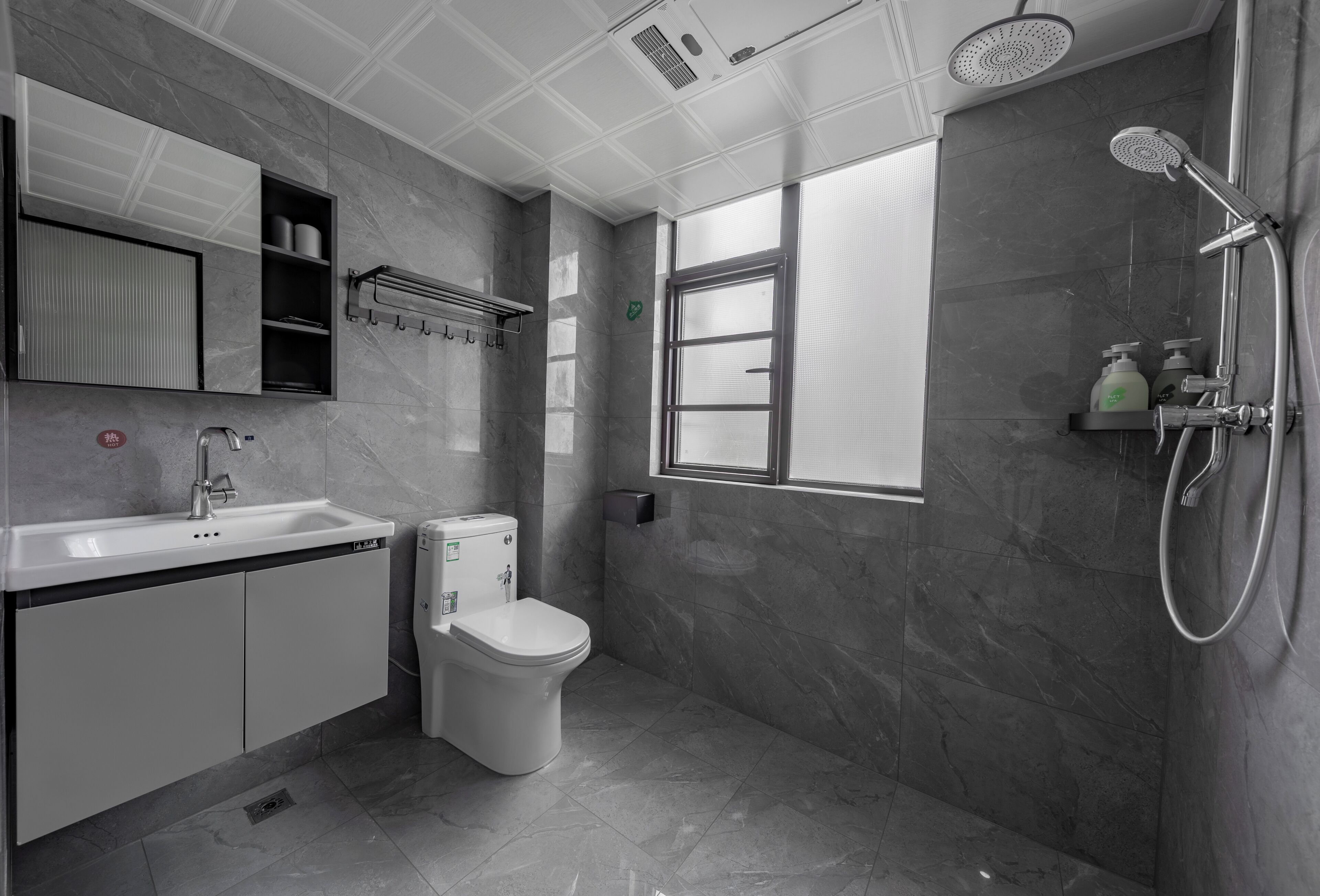 Une salle de bain moderne équipée de toilettes, d’un lavabo, d’une douche et d’une fenêtre.