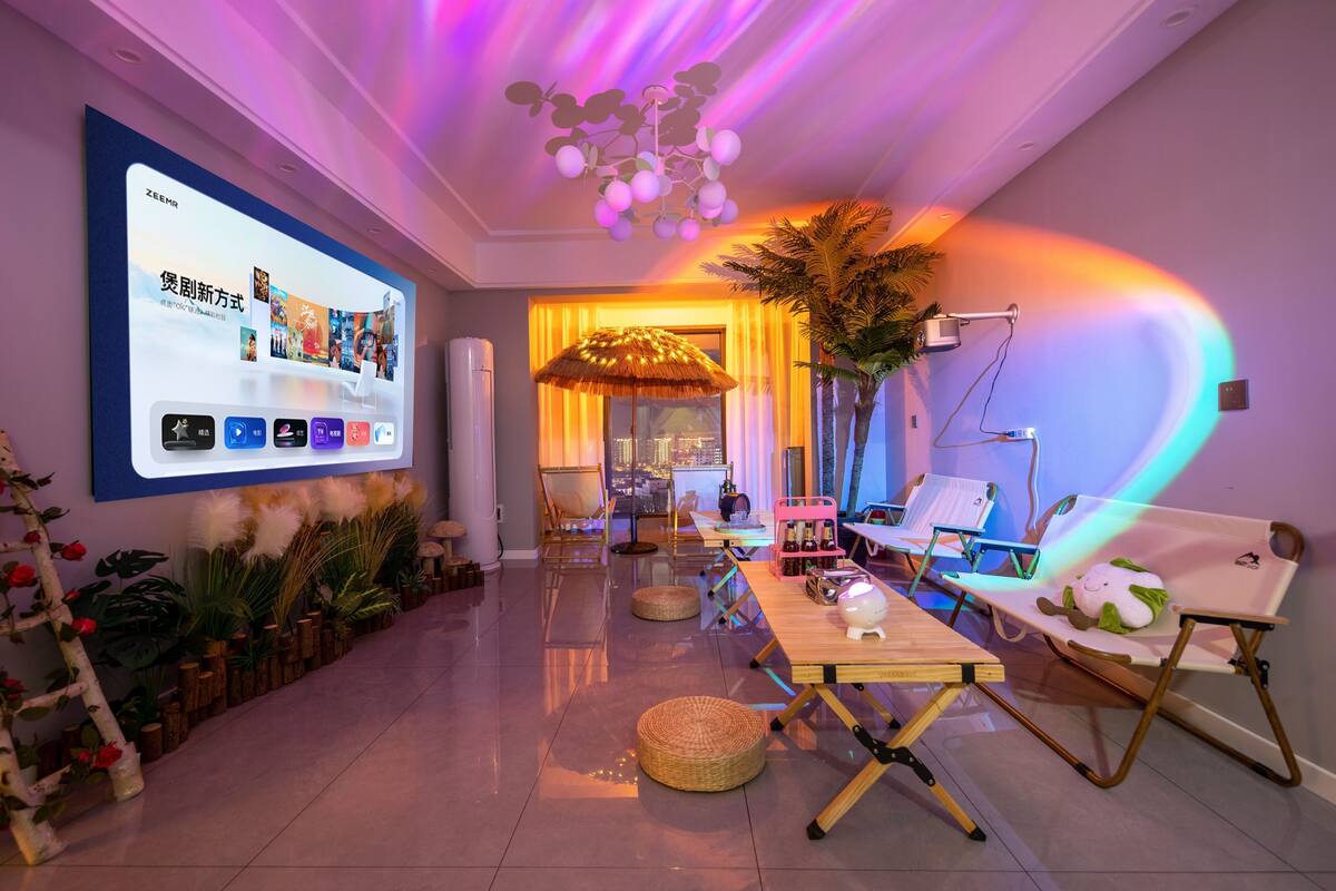 A modern living room with a large screen, comfortable seating, and a view of the city.