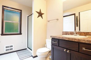 Un baño con inodoro, lavabo, espejo, decoración con estrellas y una ventana con persianas.