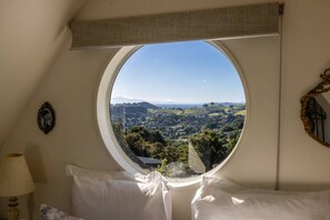 Ein Schlafzimmer mit einem runden Fenster, einem Bett, einer Lampe und einer Wanddekoration.