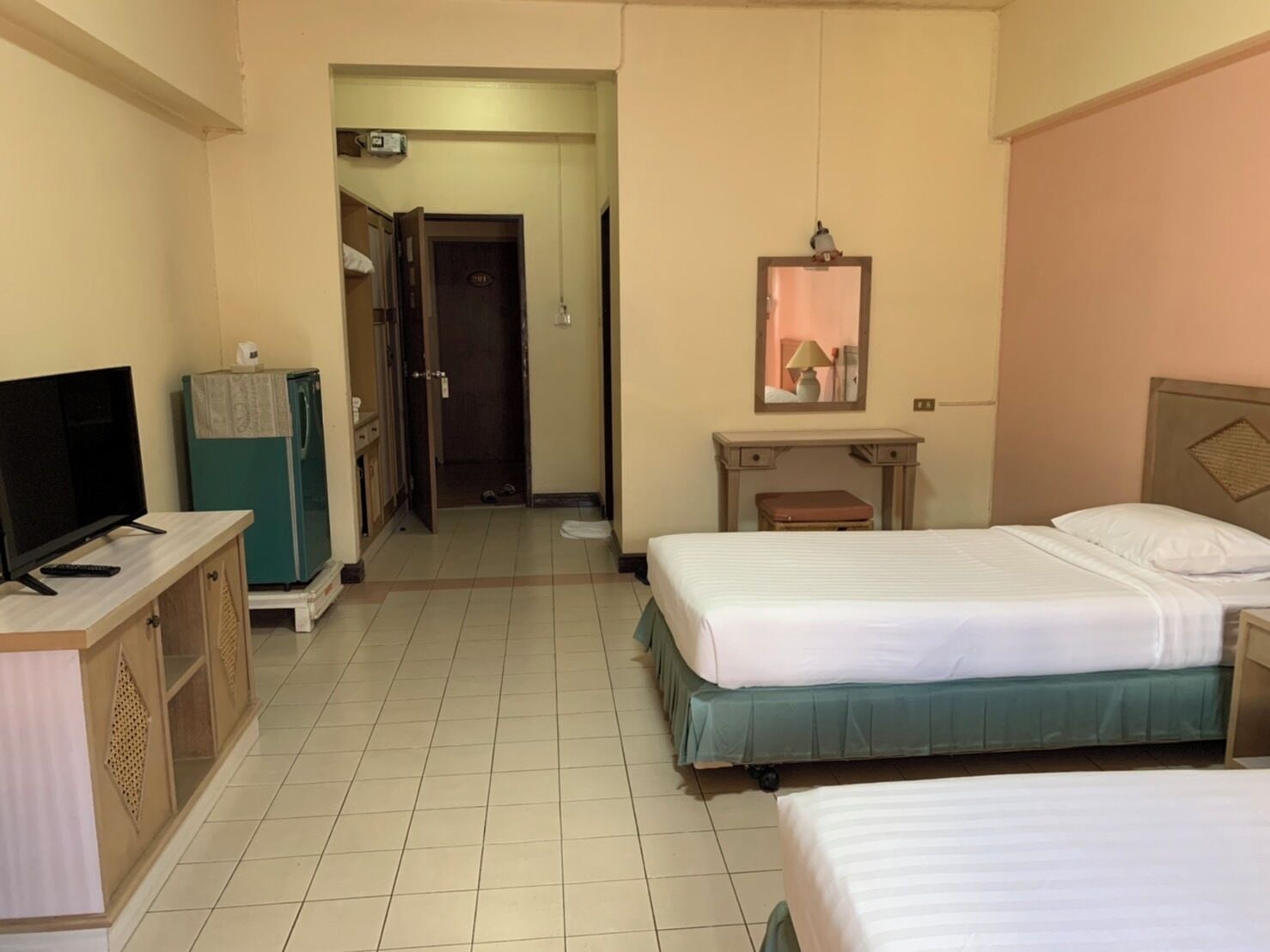 Habitación de hotel con dos camas, un escritorio, televisor y armario.