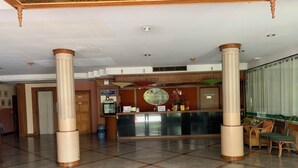 Un espace d’accueil d’hôtel comprenant un comptoir de réception, une caisse enregistreuse, un bureau d’accueil et une poubelle.