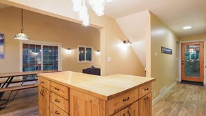 Una cocina con isla de madera, iluminación colgante y vistas al exterior.