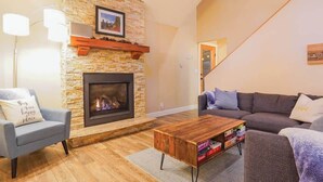 Una sala de estar con chimenea de piedra, un sofá, una mesa de centro y una lámpara.