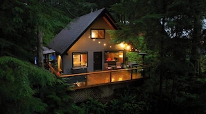 Eine Hütte mit Terrasse, großen Fenstern und Kamin.