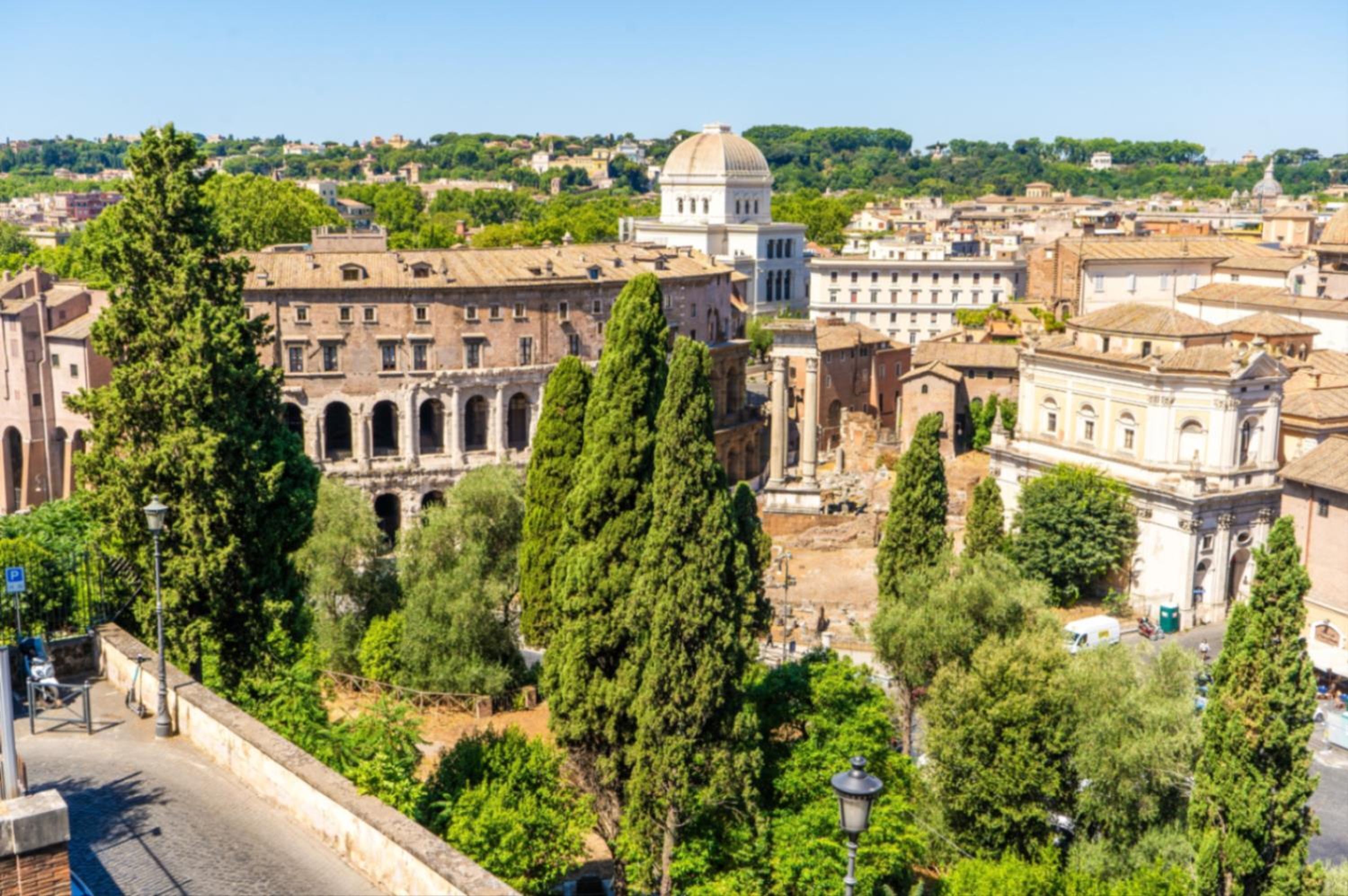 A historic building with classical architecture, including columns and arches, surrounded by trees and other buildings.