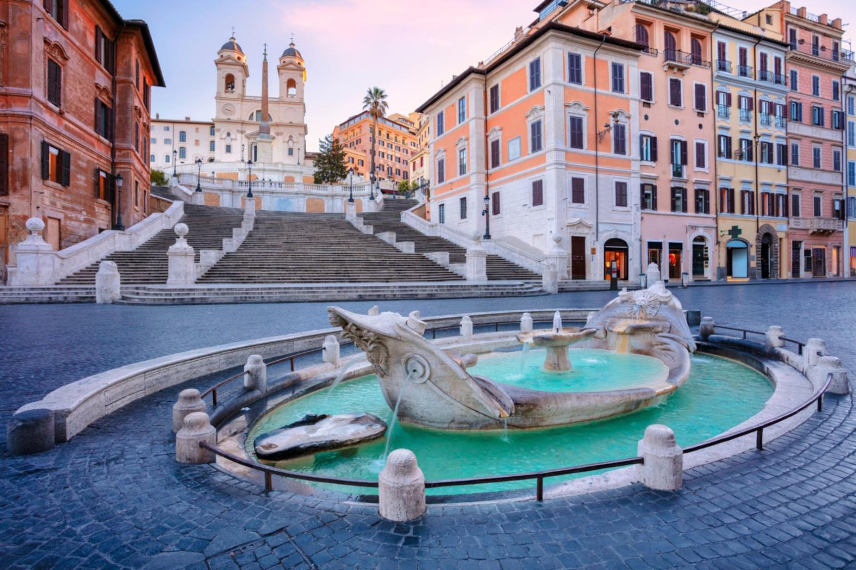 Una piazza storica con una fontana centrale, una scalinata monumentale e architettura classica.
