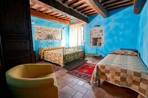 A bedroom with two beds, a wooden chair, a red rug, and a rustic ceiling. - Ottavia Residence Apartment Silver 3 Pax (Rome)