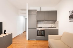 A compact kitchen with grey cabinets, a built-in oven, and a sink. - Ottavia Residence Apartment Silver 3 Pax (Rome)