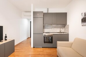 A compact kitchen with grey cabinets, a built-in oven, and a sink. - Ottavia Residence Apartment Gold 2 Pax (Rome)
