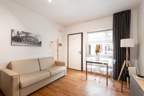 Ein modernes Zimmer mit einer Couch, einem Esstisch mit Stühlen, einer Lampe und einem Fenster mit Vorhängen.