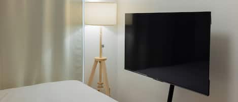 A hotel room with a bed, a wall-mounted TV, and a lamp.