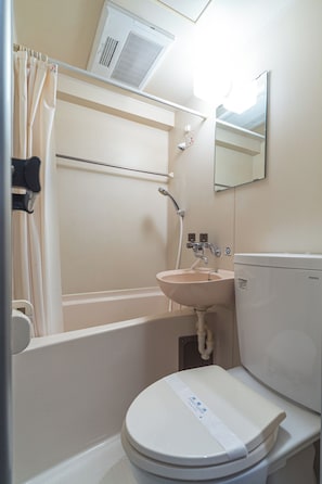 Un baño con inodoro, lavabo y zona de ducha blancos.