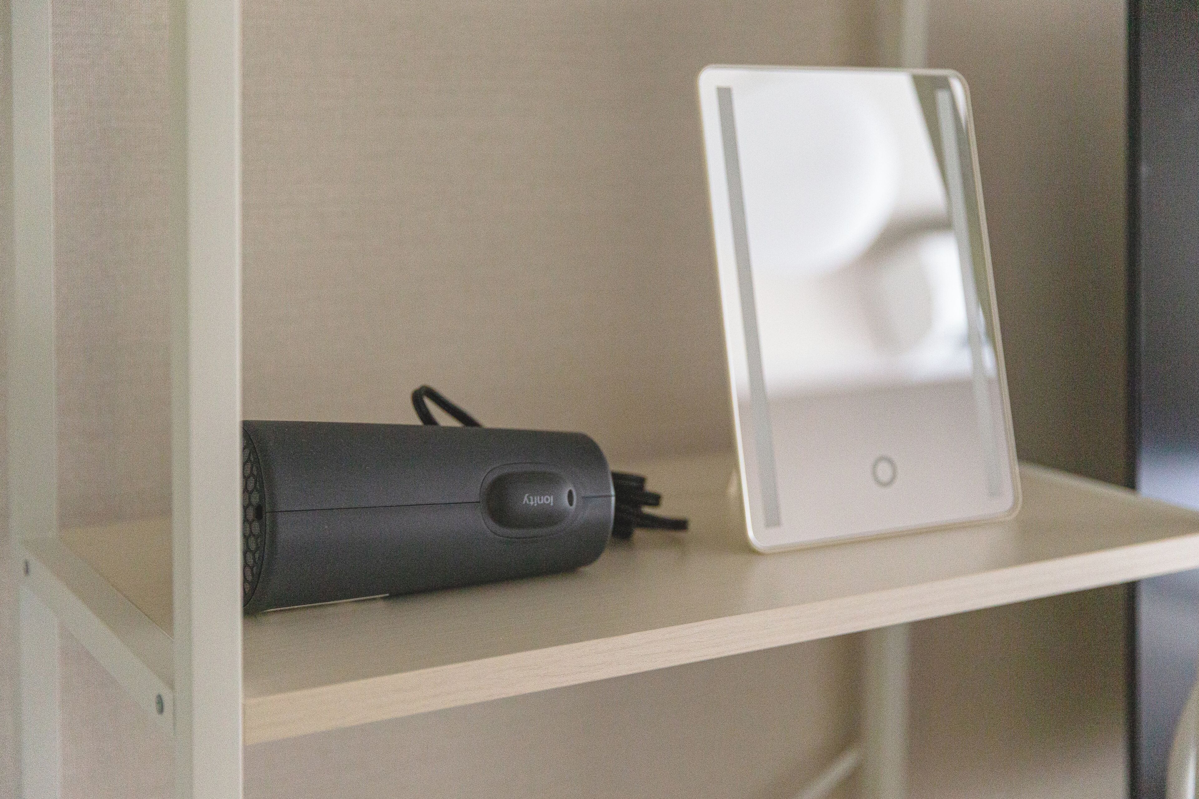 A shelf with a black cylindrical device and a white rectangular object.