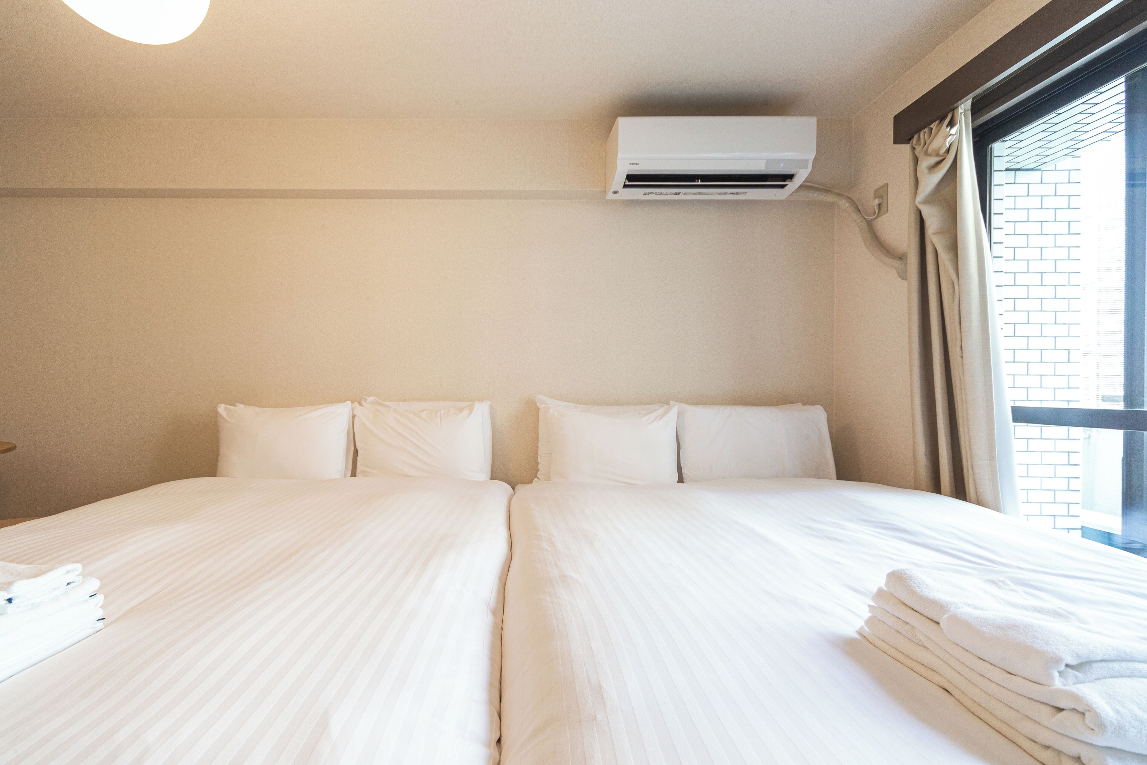 Habitación de hotel con una cama grande, aire acondicionado y una ventana con cortinas.