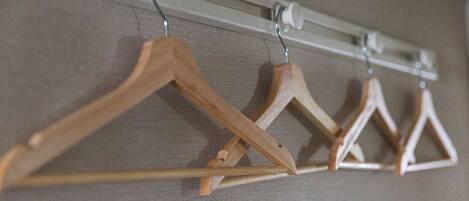 Un portant à vêtements avec des cintres en bois, placé contre un mur à texture.