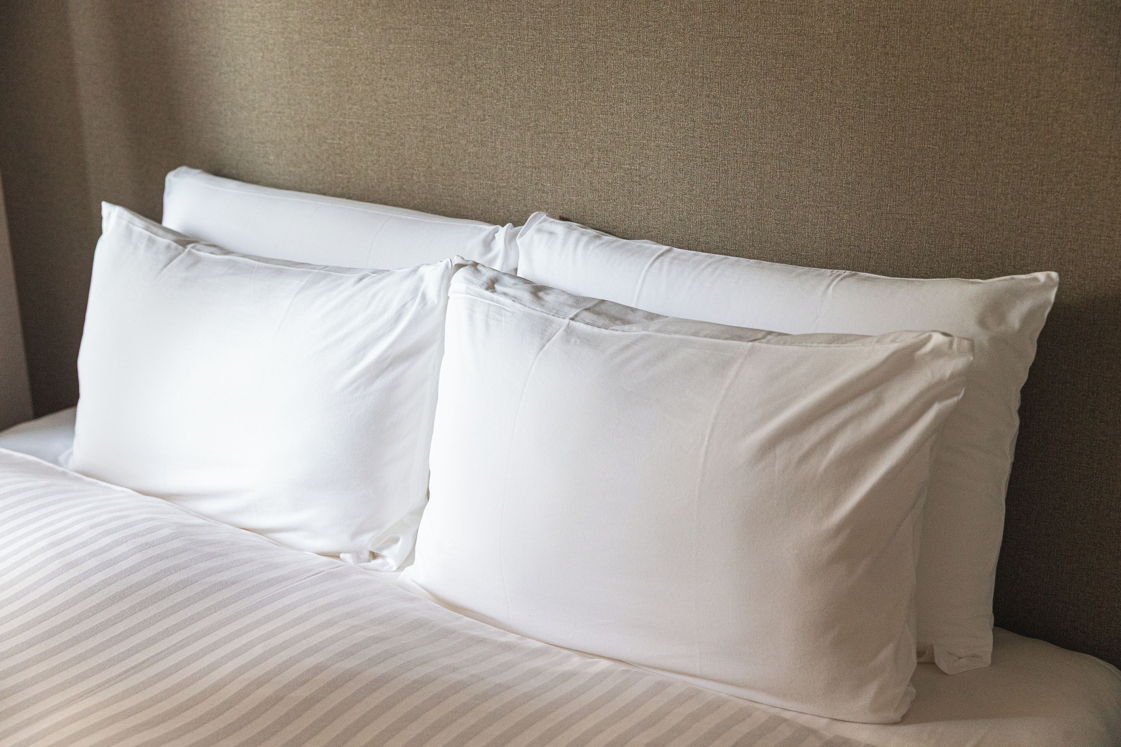 A bed with white pillows and striped bedding.