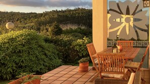 A patio with a tiled floor, wooden furniture, and potted plants. - Aire da Ría of Livinggalicia (Ortigueira)