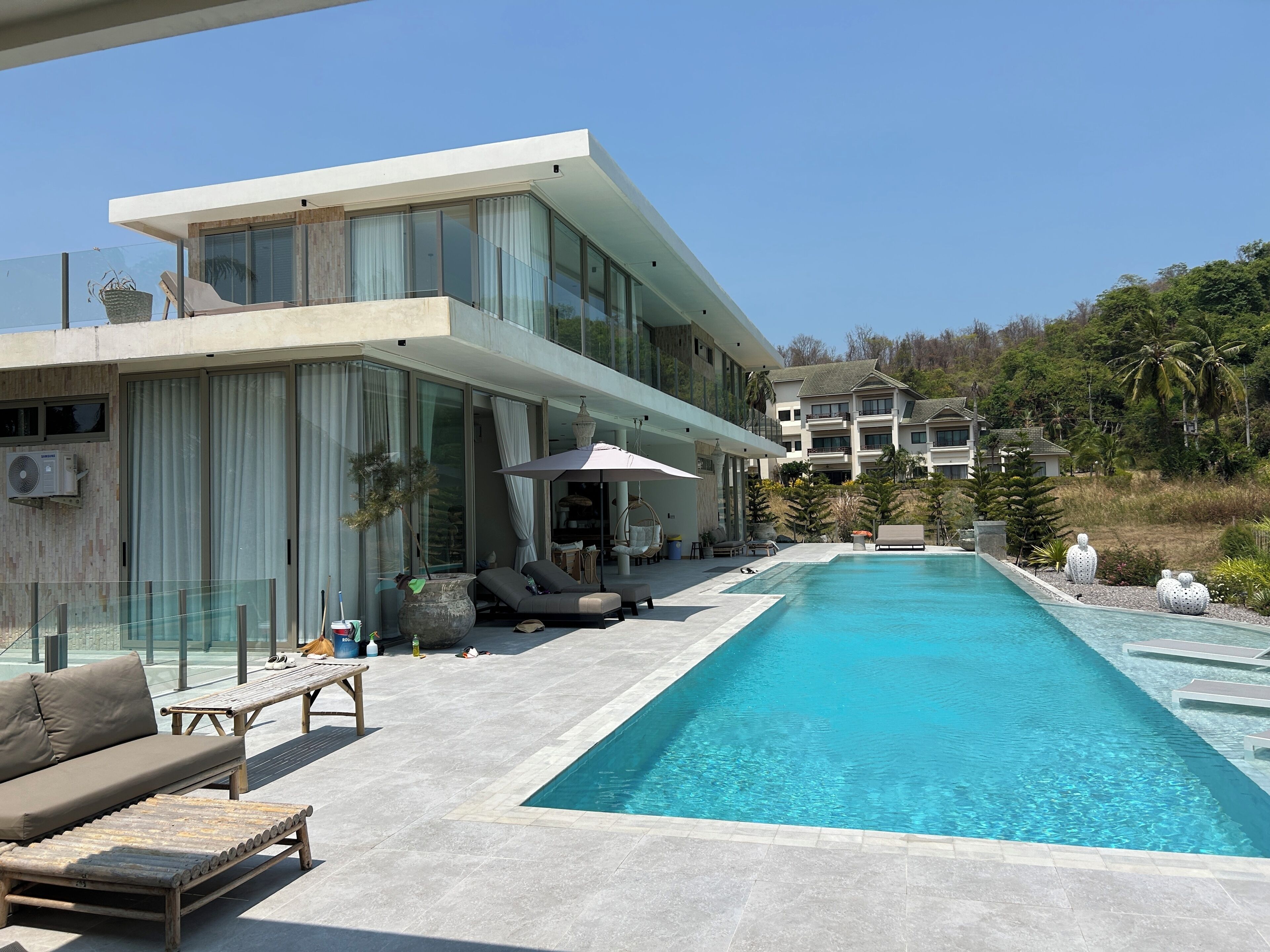 Ein modernes Haus mit Pool, Gartenmöbeln und Blick auf andere Gebäude.